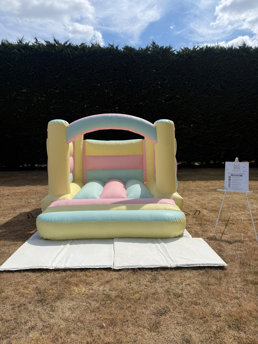 Pastel rainbow bouncy castle set up on a lawn